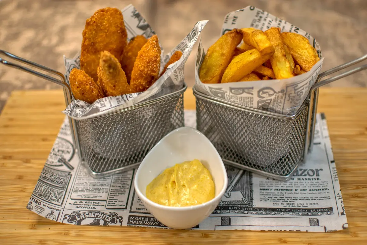 Delicious crispy chicken tenders served with fries and dipping sauce in a restaurant setting.