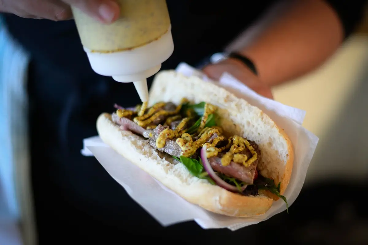 Freshly prepared sandwich with mustard sauce, perfect for a tasty street food experience on National Mustard Day.