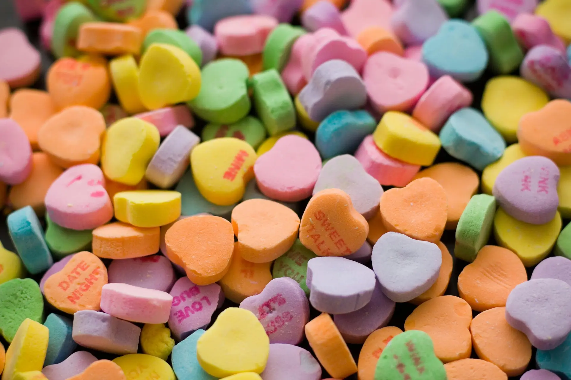 An assortment of different colored heart shaped candy.