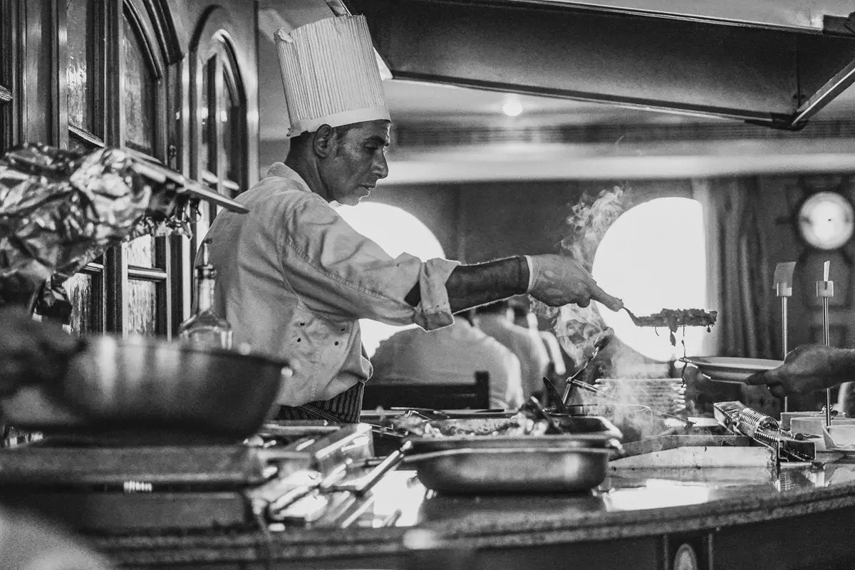 A cheif cooking in the kitchen in black and white.